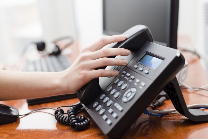 Close up on female hand holding phone at office desk